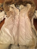 Front interior view of beige Mackage women's coat with fur trim on hood, unzipped showing padded lining.