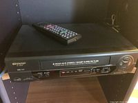 Front view of Sharp VHS VCR showing front panel with buttons and cassette slot.