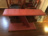 Full side view of the red patterned hall table showing the unique angled central support and rectangular top and base.