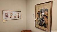 Two framed Asian wall art pieces hung on a wall, showing relative sizes and placement.