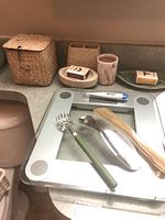 Bathroom scale with personal grooming tools and soap dishes on countertop next to toilet