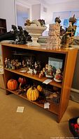 Front view of the wooden bookcase with two shelves containing various decorative figurines and pumpkins, showing the overall structure and condition.