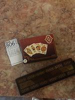 Two decks of luxury playing cards and a wooden cribbage board shown on a marble surface.