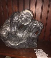 Front and side view of soapstone carving depicting Inuit man with walrus showing details of figure and texture.
