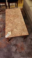Overhead view of rectangular coffee table showing pinkish marble top with natural veining and wood frame beneath