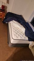 Full side view of bed assembled with mattress and comforter partially on top.