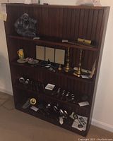 Full view of the dark wood bookcase filled with various decorative items, showing structure and shelf layout.