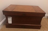 Closed view of the vintage wooden sewing box showing lock on front and tiered design.