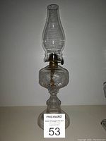 Full view of antique oil lamp showing glass chimney, brass burner, and ornate glass reservoir and base.