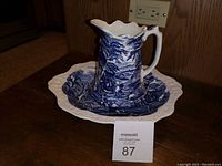 Pitcher positioned inside the bowl showing size and blue and white patterning, photo taken to illustrate complete set and condition