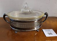 Covered Pyrex glass casserole dish placed on metal stand, showing full assembled view with lid on.
