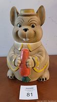 Front view of vintage ceramic cookie jar shaped like an evil bunny holding a large carrot, displaying facial details and colors.