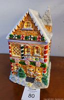 Front view of the gingerbread house cookie jar showing detailed decorations including gingerbread people, candy canes, and icing snow on the roof and around the base.