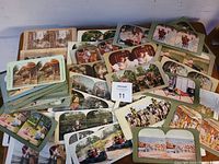 Photo showing scattered collection of over 70 stereoview cards with various images and colorings on table.