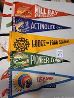 Top down photo of five different colorful vintage Canadian souvenir pennants laid out flat on a surface showing designs and text.