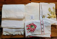 Five vintage tablecloths stacked and displayed showing the variety of designs and colors.