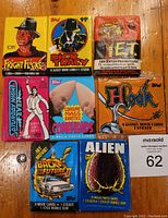 Top image showing all eight unopened vintage movie trading card wax packs from the 1970s-90s, including ET, Saturday Night Fever, Coneheads, Fright Night, Alien, Hook, Back To The Future 2, and Dick Tracy.