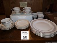 Overview of 24-piece dinnerware set showing stacked dinner plates, side plates, cups, and saucers with gold trim and black detail.