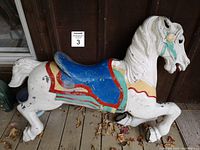 Side view of metal carousel horse showing prancing pose and saddle