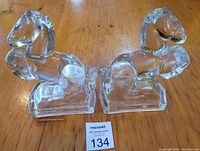 Pair of solid glass horse bookends shown side by side on a wooden table with auction lot number card.