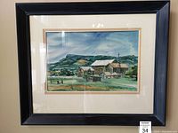 Framed watercolour painting showing rural view with barns and landscape under cloudy sky.