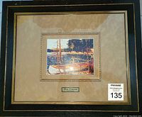 Full view of the framed print showing the art, matte, and black and gold frame with some glass reflection.