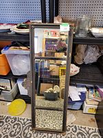 Full view of vintage rectangular mirror leaning against shelving. Shows full mirror and frame condition.