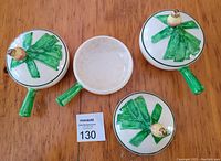 Three vintage French Onion soup bowls with lids shown from the top side. All have green handles and lids with green leaf-like decorations and yellow onion-shaped knob handles. One lid is removed showing the bowl interior with signs of staining and age.