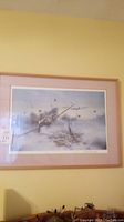 Framed airplane-themed wall art print under glass with visible reflection, on beige matte with wooden frame.