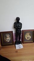 Front view showing statue flanked by two framed prints