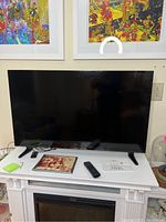 Front view of the 42-inch Insignia flatscreen TV on a white stand with remote included on the stand.