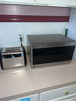 Two kitchen appliances on countertop, Hamilton Beach two slice toaster and LG microwave, side by side
