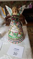 Front view of the Heartwood Creek Jim Shore New Beginnings figurine showing the angel with bouquet and painted dress scenery.