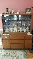 Full front view of the wooden cabinet showing glass hutch and lower storage