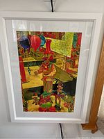 Colorful signed painting in white frame.