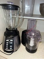 Oster blender with glass jar and food chopper attachment displayed together on a countertop.