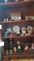 Wide shot of shelf with collectible plate, saucers, matches, figurines, basket and broken glass octopus