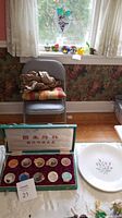Photo showing the boxed tea cup set of 6 cups and the Wedgewood plate on a table with floral wallpaper background.