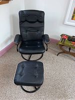 Front view of black leather swivel chair with matching footrest on carpet