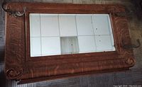 Full view of wooden mirror showing wood frame and mirror surface with visible black dots and scratches.