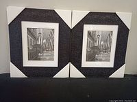 Two black textured photo frames standing side by side with white corner covers on.