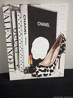Front view of largest canvas wall art showing Chanel themed design with lipstick and leopard print shoe next to fashion book spines
