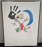 Frontal view of lithograph showing colorful abstract artwork with black handprint, blue crescent moon, star, and artist's signature.