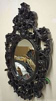 Front view of the large mirror showing ornate black frame and oval glass