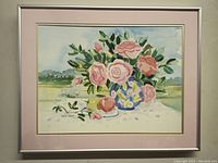 Framed watercolor painting of pink roses in a decorative blue and yellow vase on a white surface against a green scenic background.