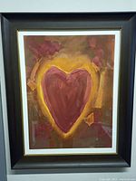 Framed lithograph artwork showing a heart in red and yellow tones with abstract red shapes. Signed by artist Pedie Wolfond, displayed in black wooden frame with white matting.
