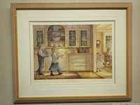 Framed print of the artwork showing a warm kitchen birthday scene with a man and woman carrying gifts and cake