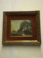 Full view of framed artwork showing rural road with trees, rustic houses, ornate gold tone frame and burnt orange velvet mat