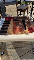 Photo of abstract rectangular area rug with brown, red, and tan geometric shapes and black striping.