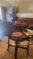 Photo showing the assorted woven baskets on a glass table, including a large cylindrical basket, a rectangular basket with handles, and other smaller baskets